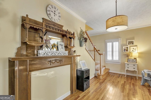 interior space with a textured ceiling, baseboards, stairway, light wood finished floors, and crown molding