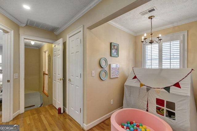 playroom featuring light wood-style floors, visible vents, and ornamental molding