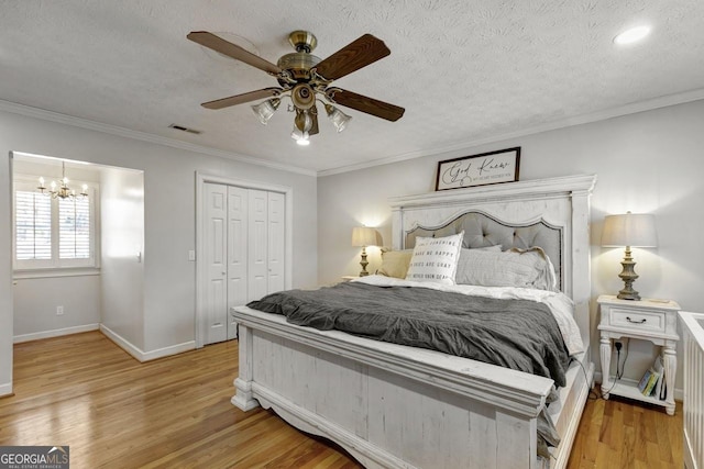 bedroom featuring light wood finished floors, visible vents, ornamental molding, a textured ceiling, and a closet