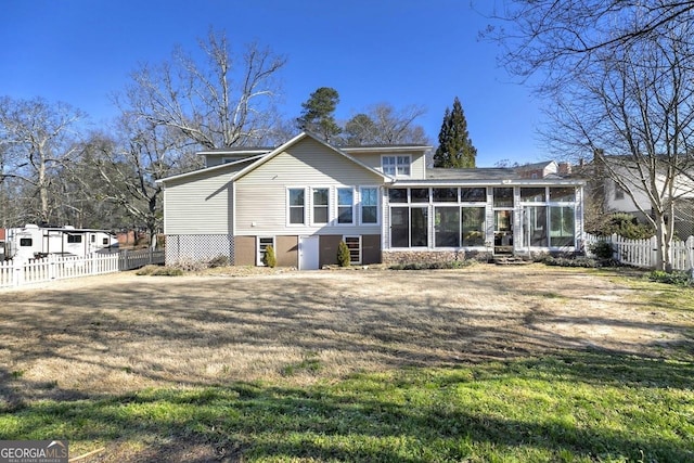 rear view of property featuring a sunroom, fence, and a yard