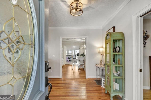 entrance foyer with ornamental molding, a textured ceiling, baseboards, and wood finished floors