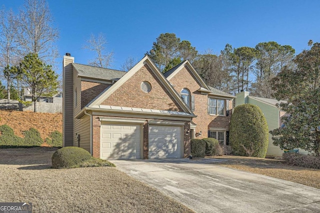 traditional home featuring a garage, brick siding, driveway, and a chimney