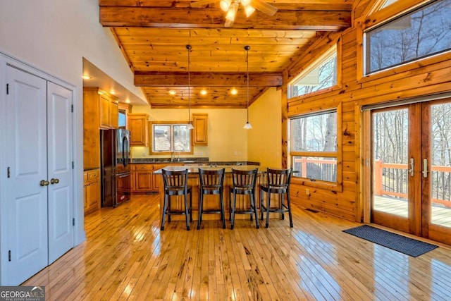 dining area with wood ceiling, beam ceiling, light wood-style flooring, and french doors