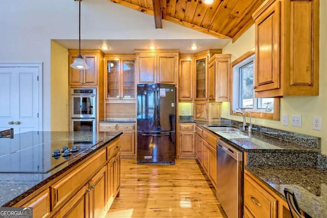 kitchen featuring brown cabinets, vaulted ceiling, black appliances, pendant lighting, and a sink