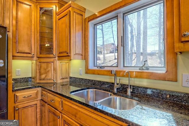 kitchen featuring glass insert cabinets, a wealth of natural light, brown cabinets, and a sink