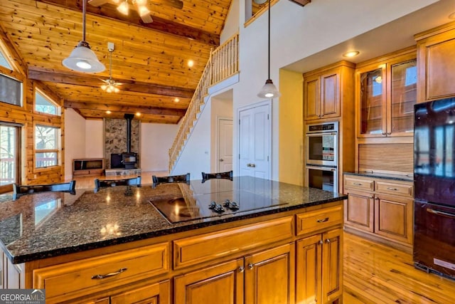 kitchen with black electric stovetop, double oven, wood ceiling, a wood stove, and open floor plan