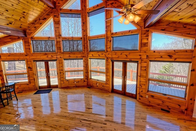 unfurnished living room with wood ceiling, wood-type flooring, french doors, wood walls, and high vaulted ceiling