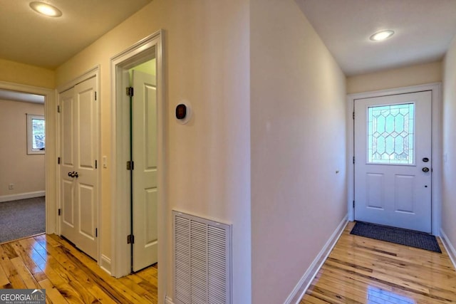 doorway with light wood-type flooring, visible vents, and baseboards