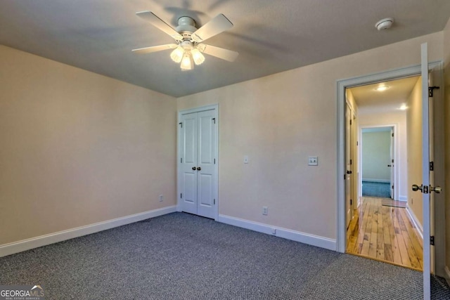 unfurnished bedroom featuring a ceiling fan, carpet, a closet, and baseboards