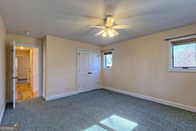 unfurnished bedroom with ceiling fan, a closet, carpet flooring, and baseboards