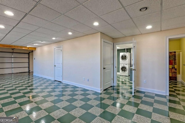 interior space featuring a paneled ceiling, baseboards, and stacked washer / drying machine