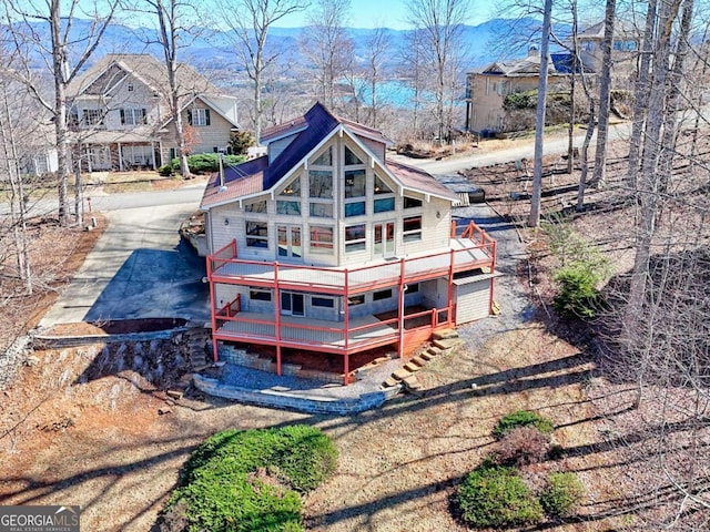 rear view of property with driveway and a wooden deck