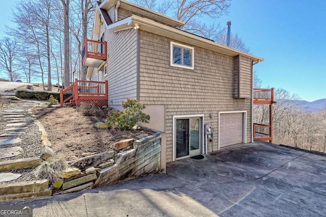 rear view of property with a garage, concrete driveway, and a balcony