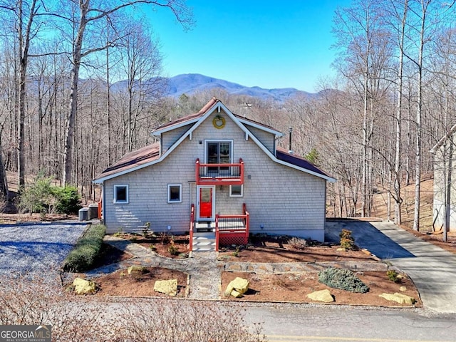 view of front of property featuring a balcony, driveway, central AC unit, and a mountain view