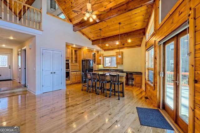 kitchen with light wood-style flooring, a breakfast bar, wood ceiling, brown cabinetry, and dark countertops