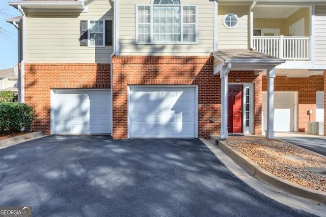 view of front of home featuring a garage, cooling unit, brick siding, and driveway