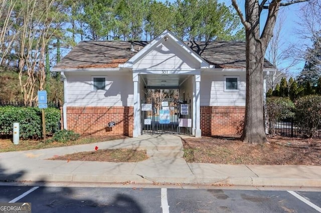 view of front of property featuring uncovered parking, a gate, brick siding, and fence