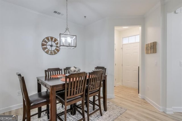 dining room featuring baseboards, visible vents, ornamental molding, an inviting chandelier, and light wood-type flooring