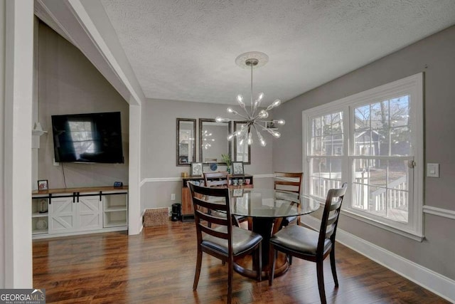 dining space with a chandelier, a textured ceiling, baseboards, and wood finished floors