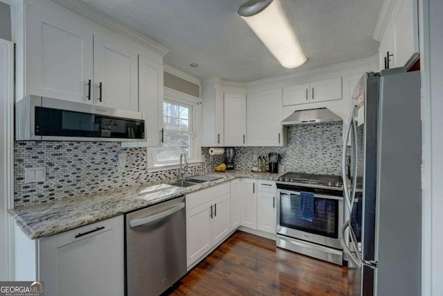 kitchen featuring stainless steel appliances, wall chimney range hood, a sink, and white cabinets