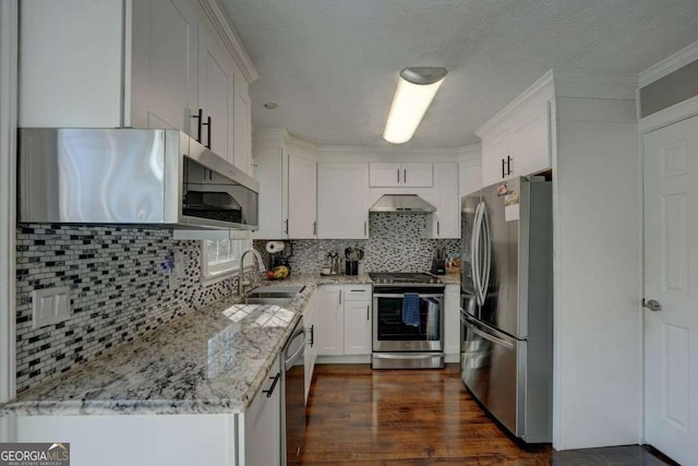 kitchen with light stone counters, a sink, white cabinets, wall chimney range hood, and appliances with stainless steel finishes