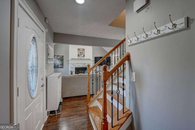 foyer entrance with a fireplace, stairway, and wood finished floors