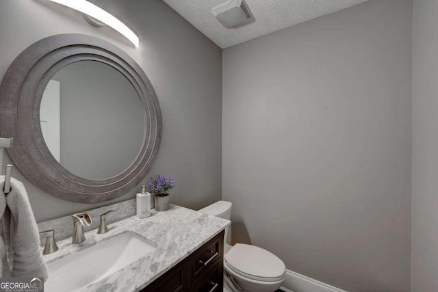 bathroom with baseboards, visible vents, toilet, a textured ceiling, and vanity