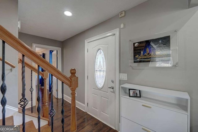 entrance foyer with dark wood-style floors, baseboards, stairway, and a textured ceiling