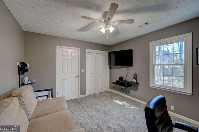 office featuring carpet floors, visible vents, ceiling fan, a textured ceiling, and baseboards