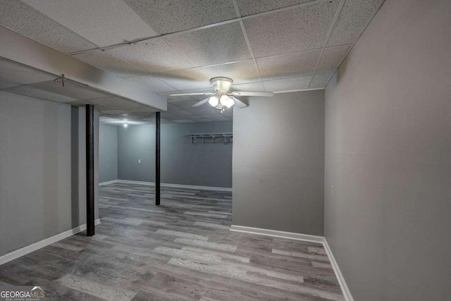 interior space with a drop ceiling, baseboards, and wood finished floors