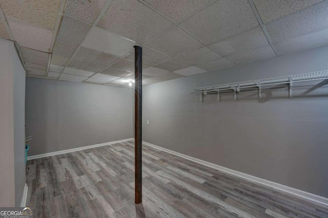 finished basement featuring a drop ceiling, baseboards, and wood finished floors