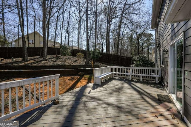 wooden terrace with a fenced backyard