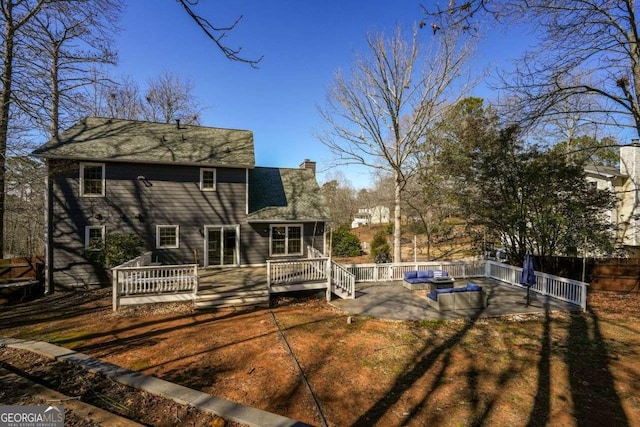 rear view of property featuring a patio area, a chimney, a wooden deck, and a fenced backyard