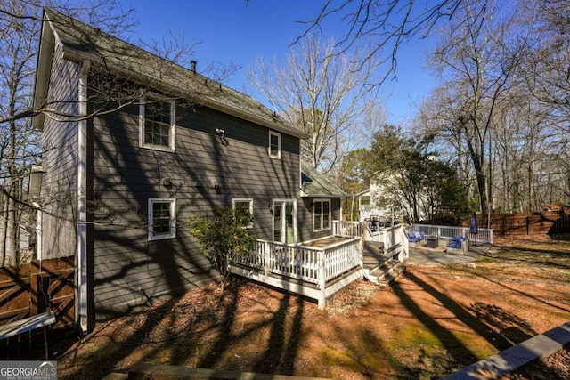 rear view of house featuring fence and a wooden deck