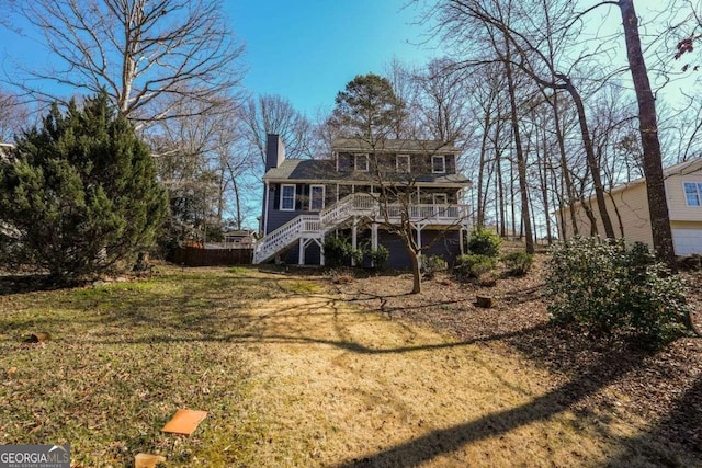 back of property featuring stairway, a chimney, and a lawn