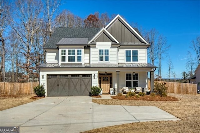 craftsman house featuring covered porch, board and batten siding, a standing seam roof, fence, and driveway