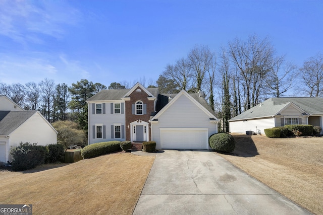 colonial-style house featuring a garage, driveway, and brick siding