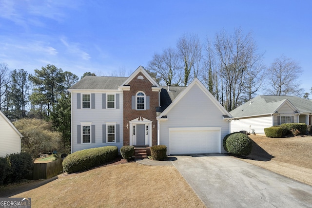 colonial home with concrete driveway, brick siding, an attached garage, and fence