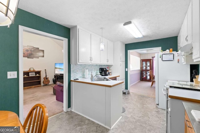1800 Rockdale Cir, Snellville, GA 30078 - kitchen featuring decorative light fixtures, a peninsula, light countertops, a textured ceiling, and white cabinetry