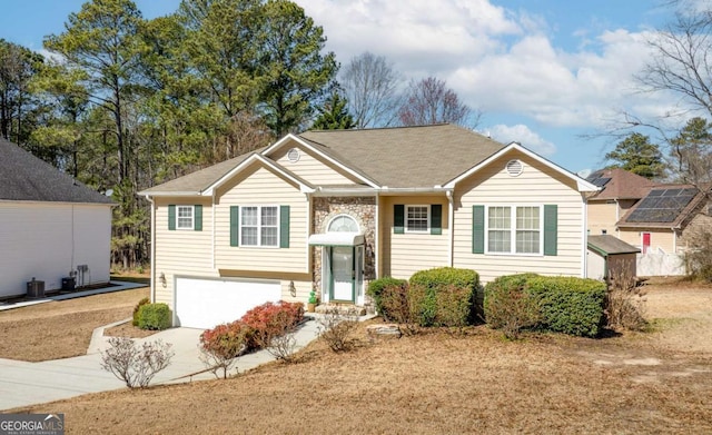 raised ranch featuring a garage and concrete driveway