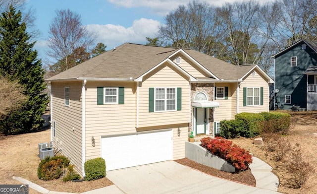 split foyer home with concrete driveway, central AC, and an attached garage