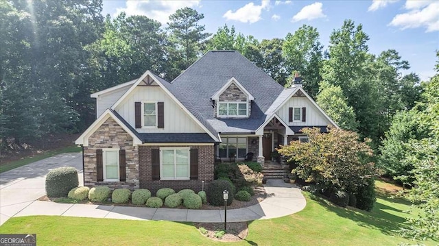 craftsman inspired home with stone siding, brick siding, a front lawn, and roof with shingles