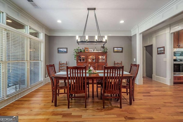 dining area featuring ornamental molding, light wood-type flooring, visible vents, and a notable chandelier