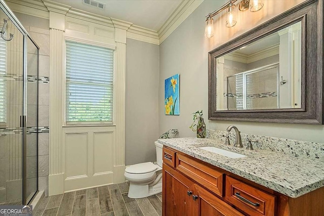 bathroom with a stall shower, toilet, ornamental molding, vanity, and wood finish floors