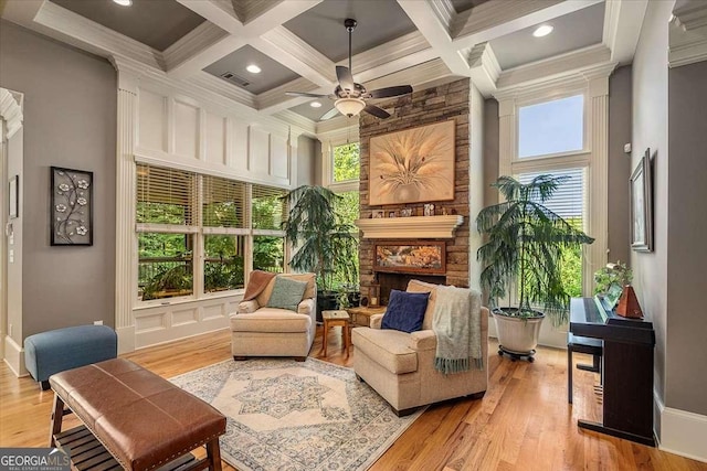 sitting room with visible vents, a towering ceiling, a stone fireplace, coffered ceiling, and beamed ceiling