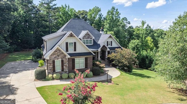 craftsman-style home with brick siding, stone siding, concrete driveway, a front lawn, and board and batten siding