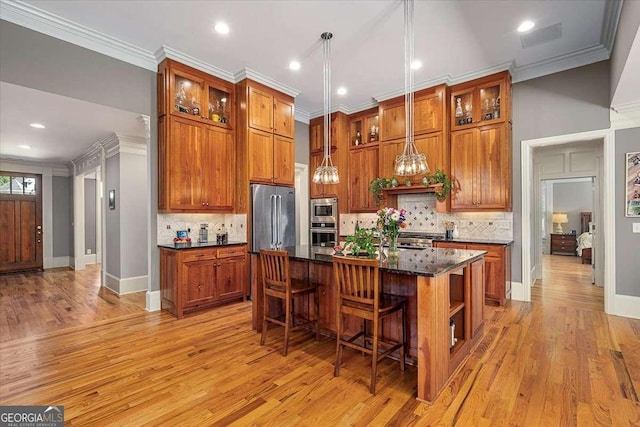 kitchen with appliances with stainless steel finishes, brown cabinets, and crown molding