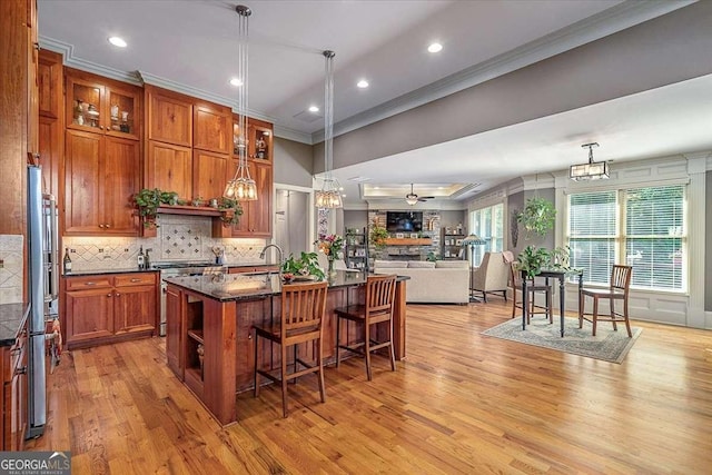 kitchen featuring stainless steel stove, brown cabinets, decorative backsplash, a kitchen bar, and crown molding