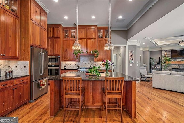 kitchen featuring stainless steel appliances, a kitchen island with sink, ceiling fan, and crown molding