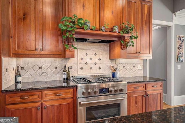 kitchen with backsplash, brown cabinets, dark stone countertops, and high end stainless steel range